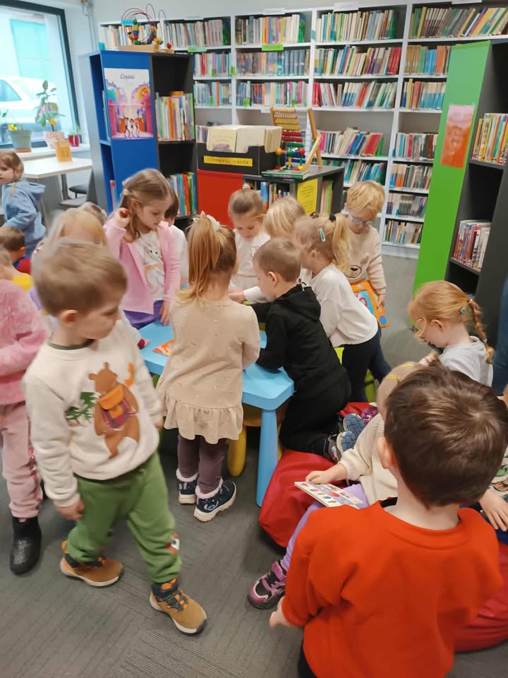 Grupa dzieci wesoło przeglądająca książki.